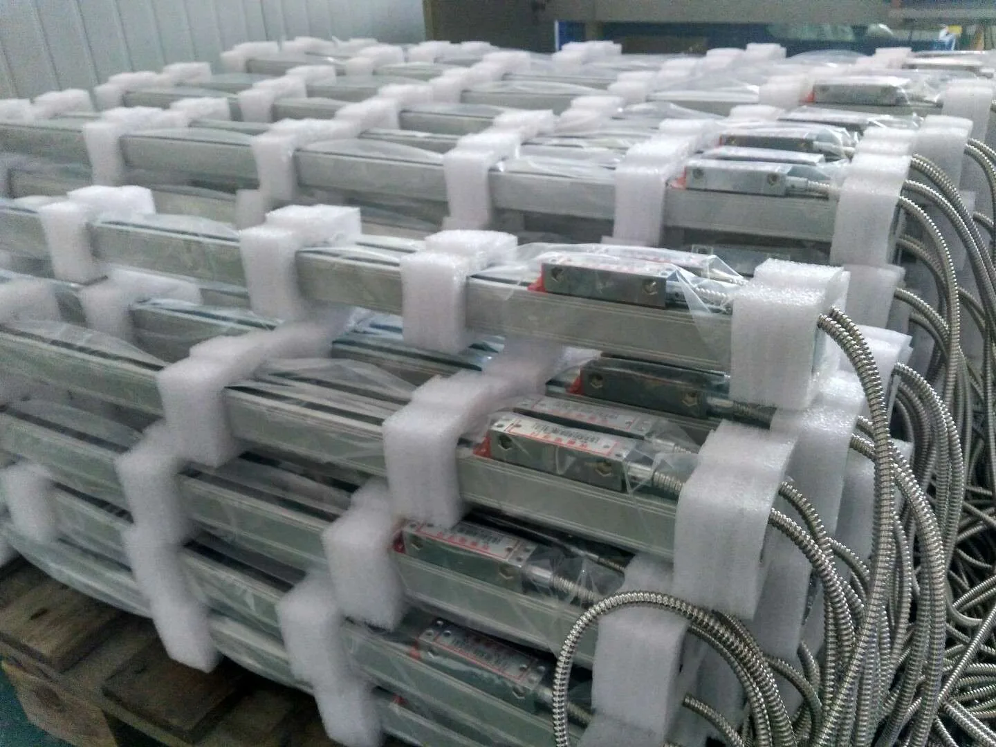 Linear scales stacked with foam protection alongside their coiled stainless connecting cables.