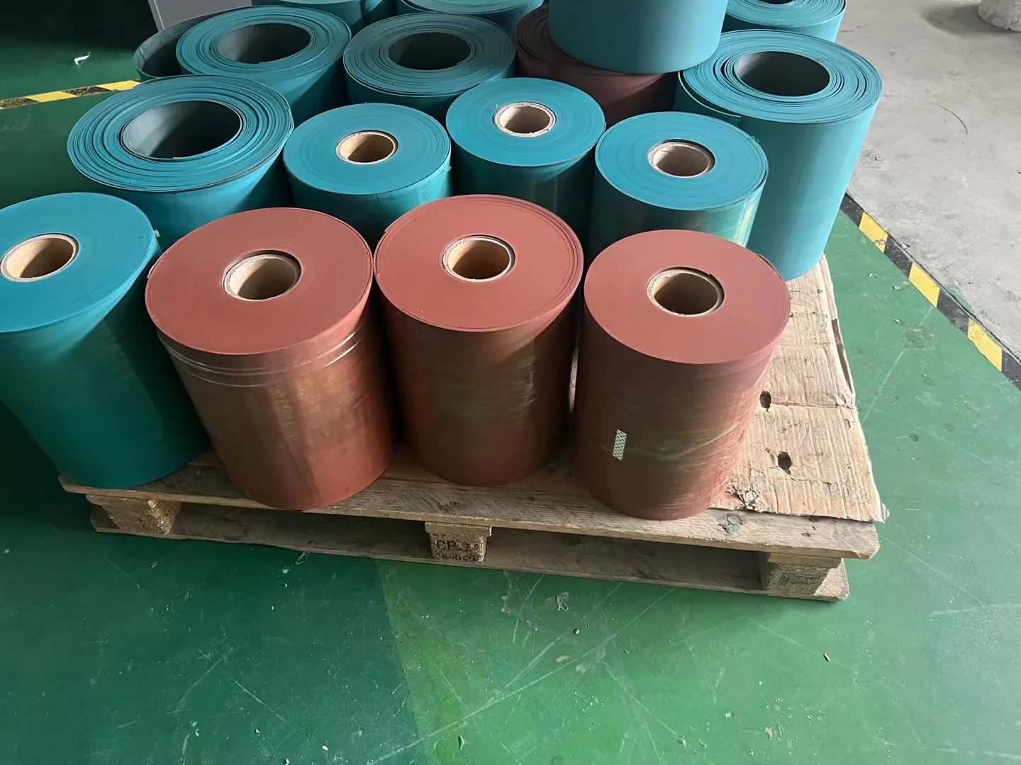 Rolls of Turcite B type lining sheet on a pallet, in the cyan and brick-red colours listed in the category.