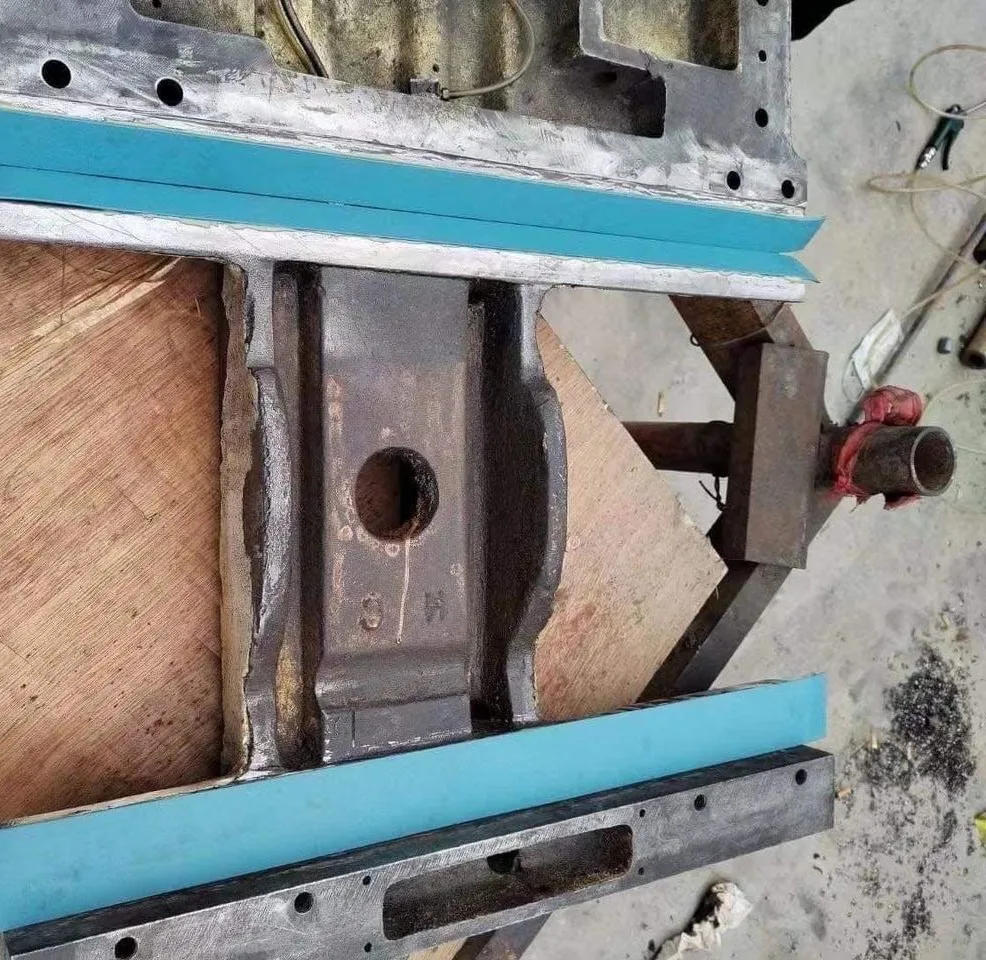 A cast-iron machine saddle on a bench with light-blue Turcite B strips cut and laid on the dovetail ways before bonding.